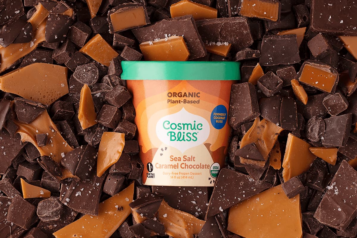 A pint of sea salt caramel chocolate ice cream sitting on top of chocolate and caramel chunks